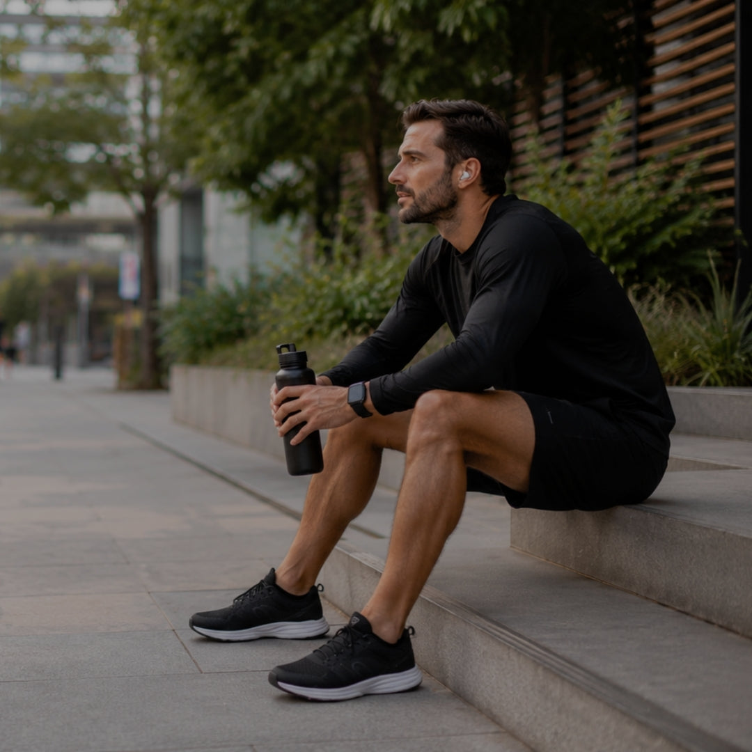 Man sitting on steps outdoors holding a water bottle