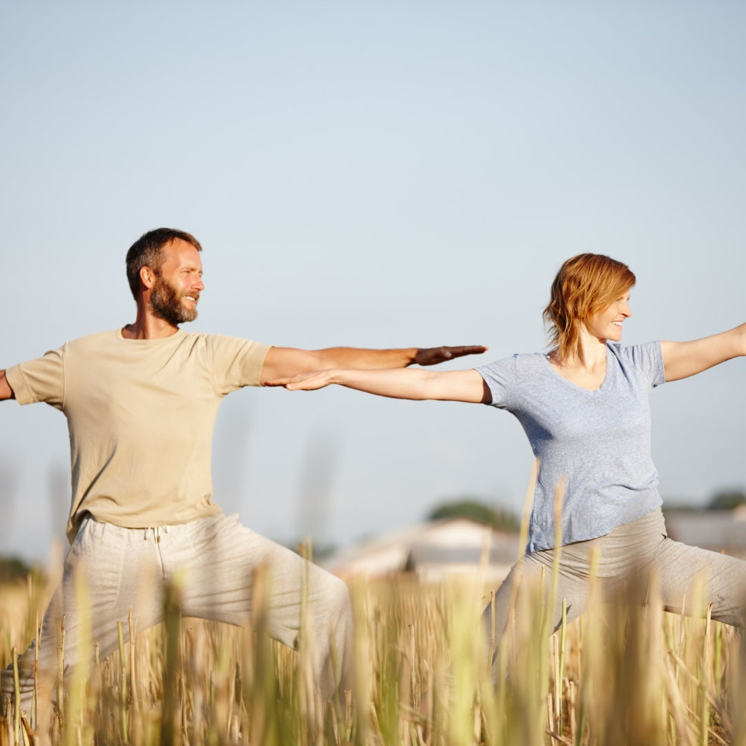 Man and woman holding hands in a field with a clear sky
